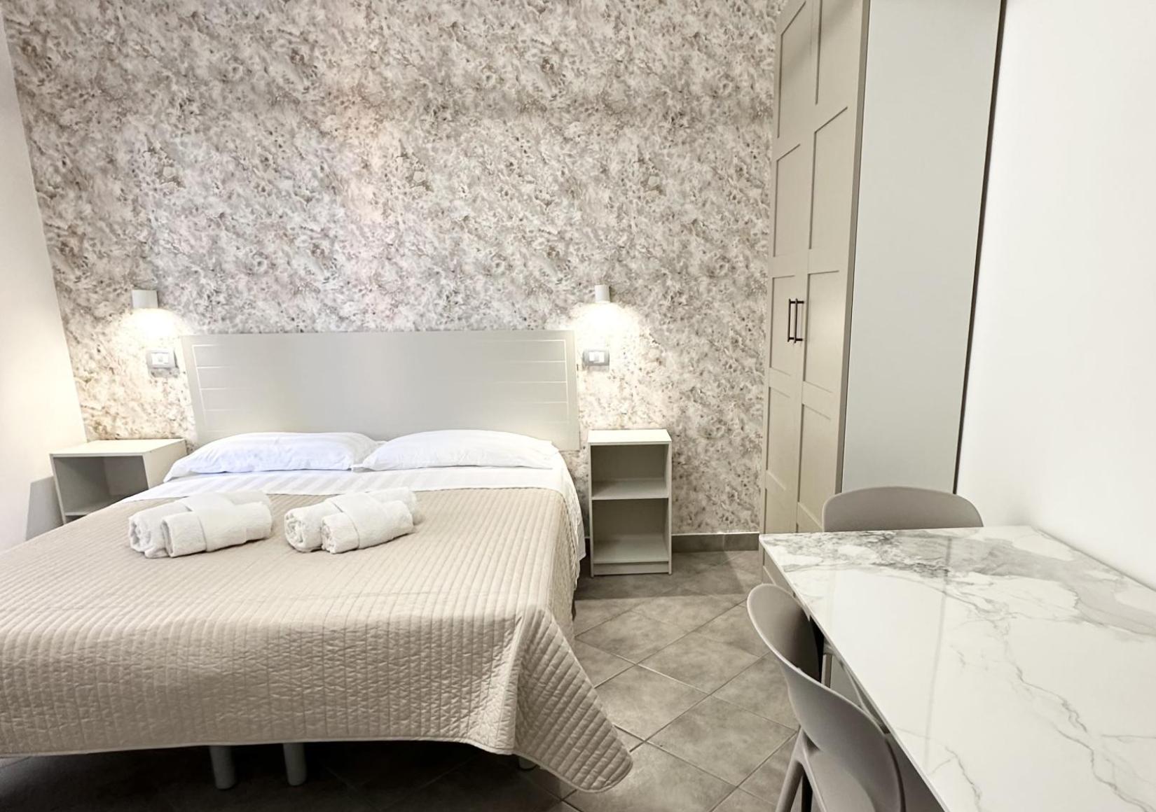 Modern room with double bed, table, chairs, and elegant lighting.
