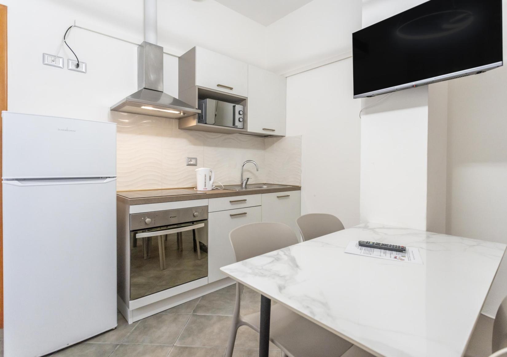 Modern kitchen with appliances, dining table, and wall-mounted TV.