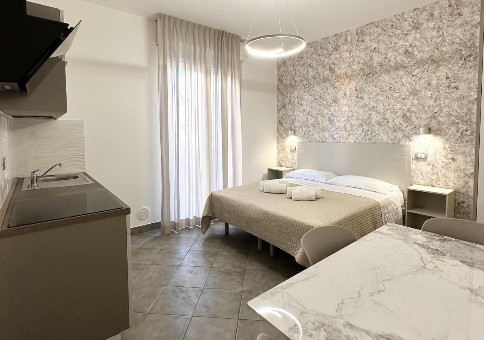 Modern studio with kitchenette, double bed, and dining table.