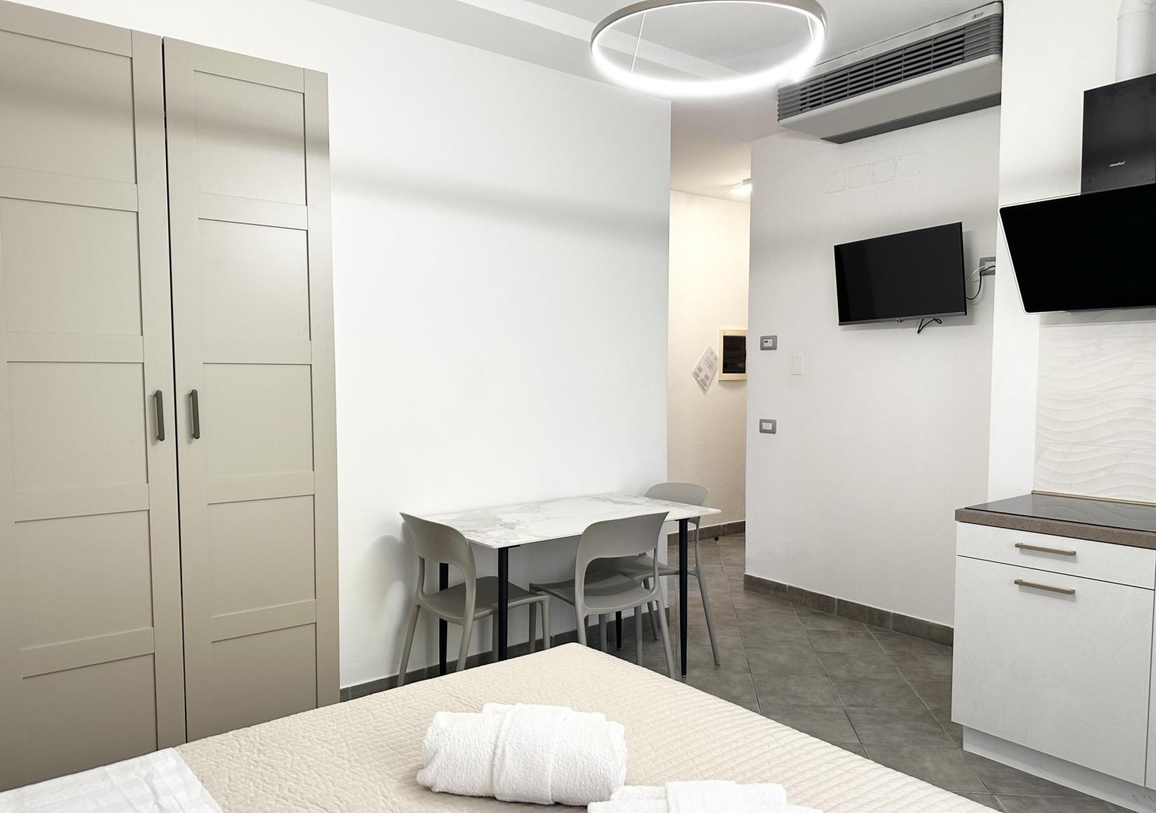 Modern room with bed, wardrobe, table, and flat-screen TV.